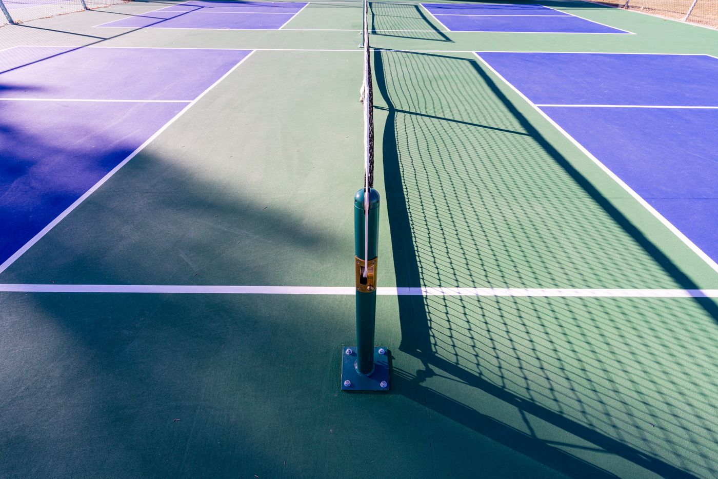 Sunlit pickleball court with a net and painted playing lines